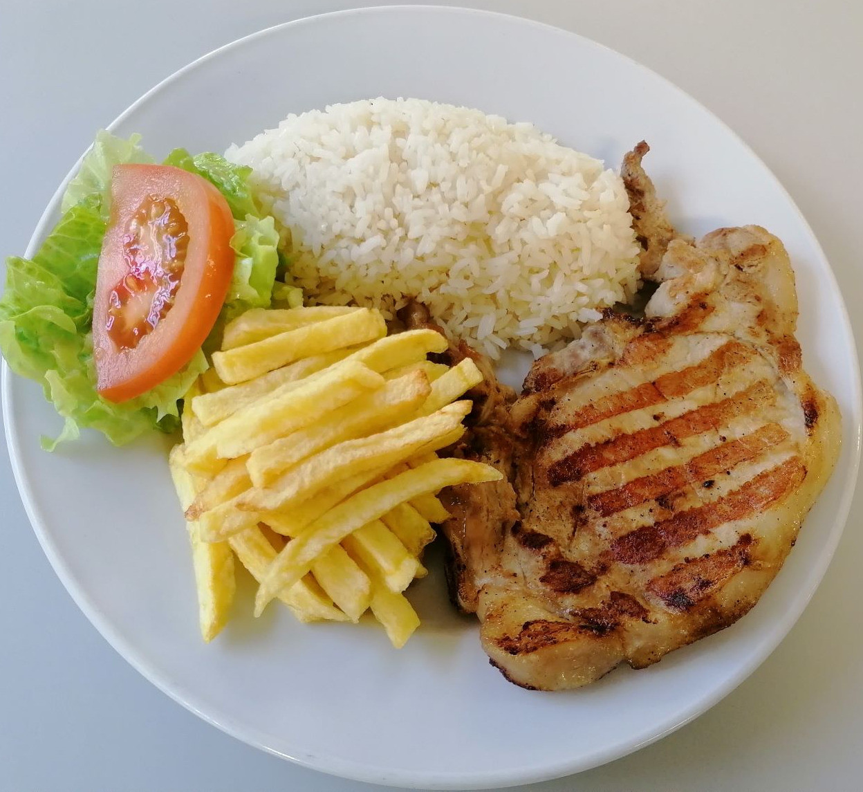 Costeletas de porco grelhadas com arroz e batata frita