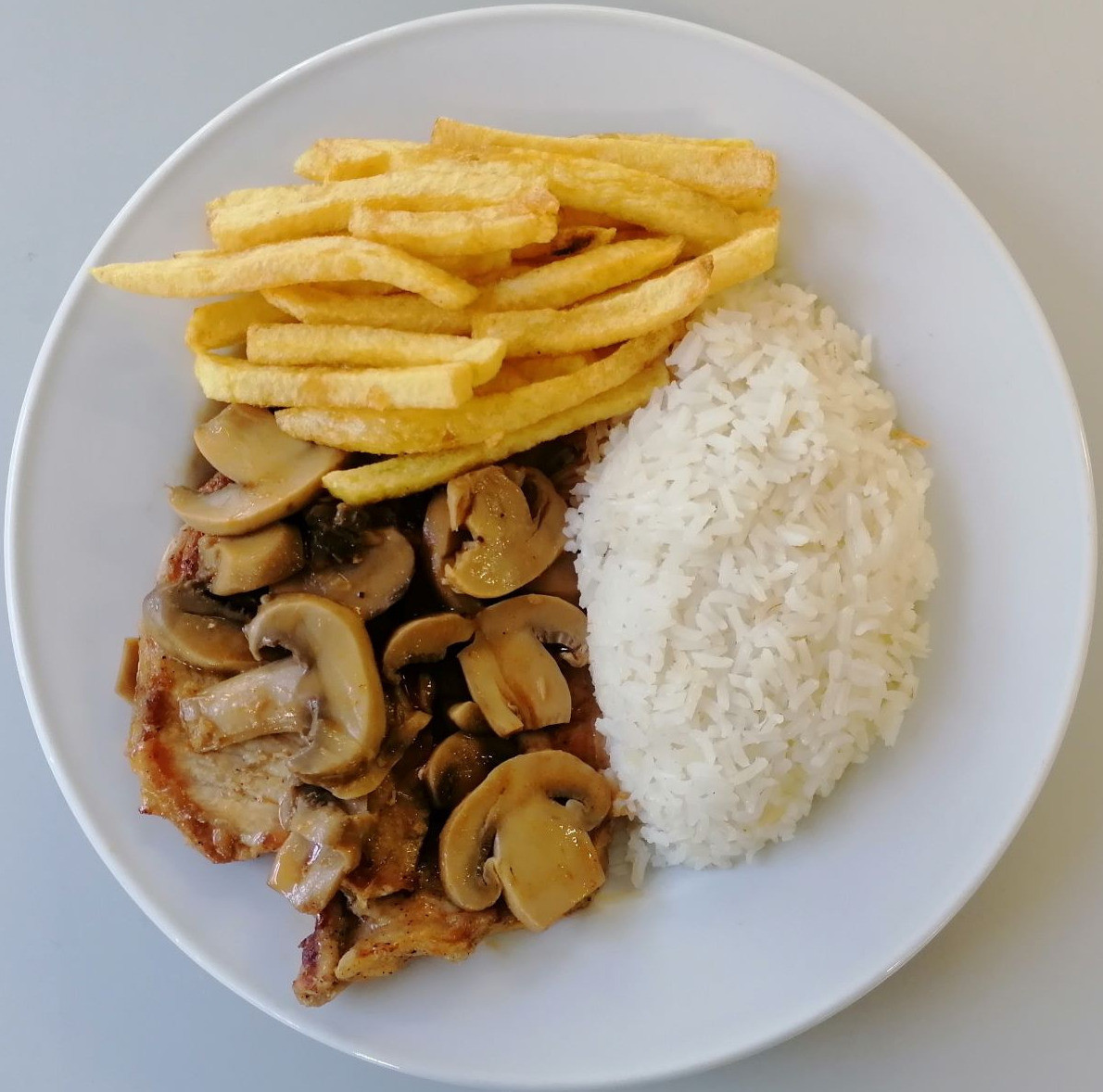 Bifinhos de porco com molho de cogumelos, arroz e batata frita